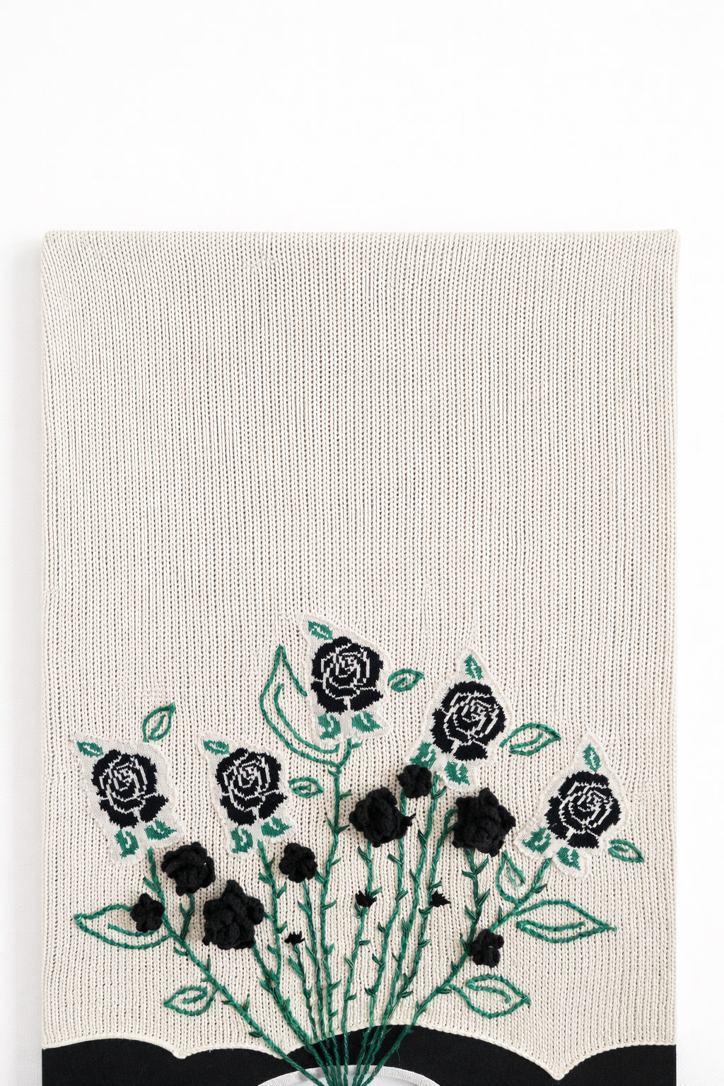 close up of hand loomed cotton knit background textile with embroidered vines and black rose details