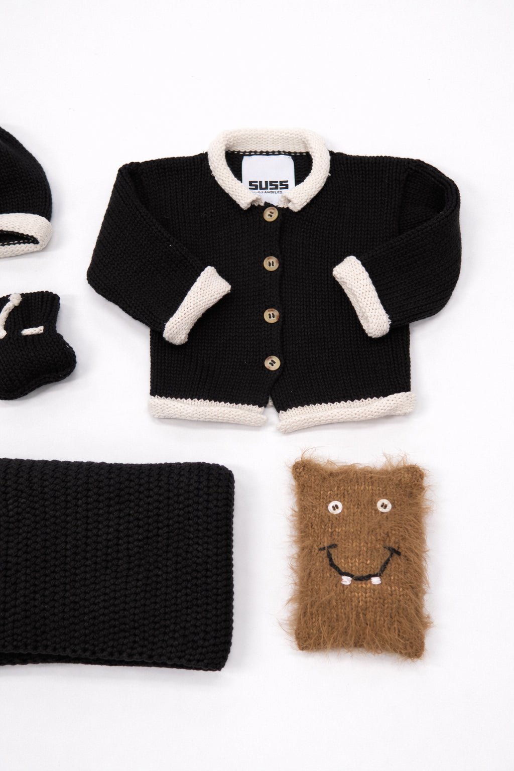 Close up of set of cotton black and cream baby cardigan and knit texture detail