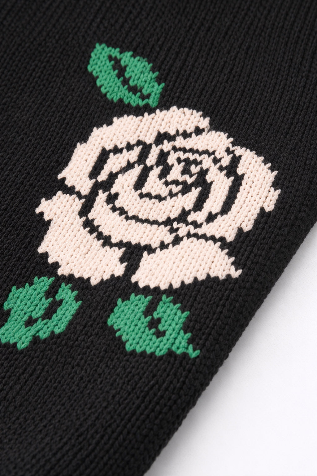 Close-up of red rose intarsia knit detail on black cotton sweater by Suss Knits
