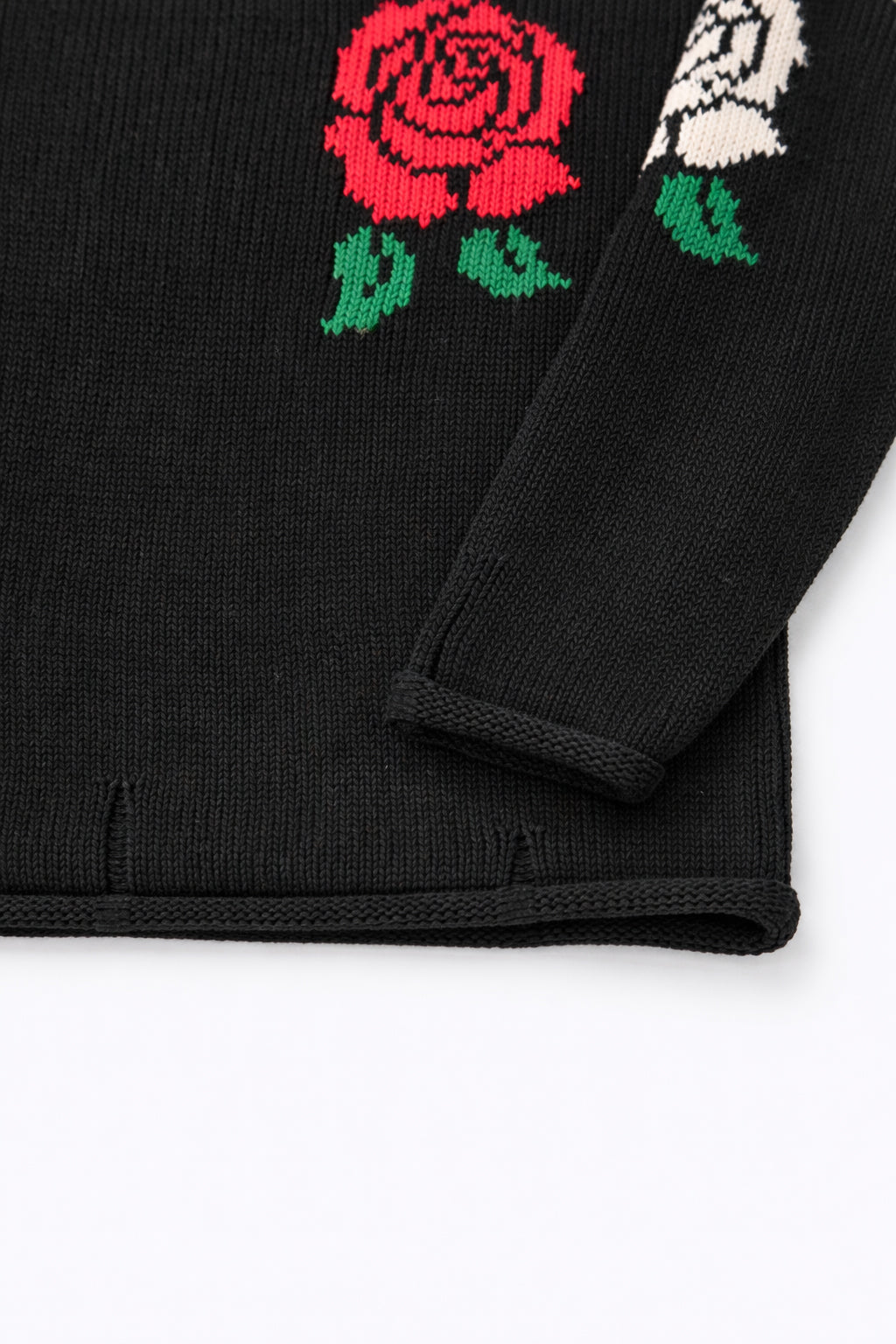 Sleeve and hem detail of black cotton knit sweater with rose intarsia by Suss Knits