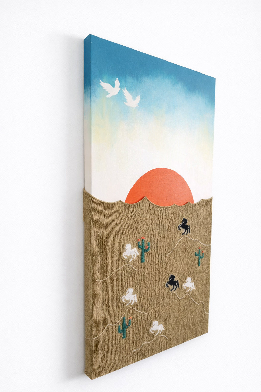 suss knits side angled view of hand loomed textile wall art with desert sunset and embroidered horses