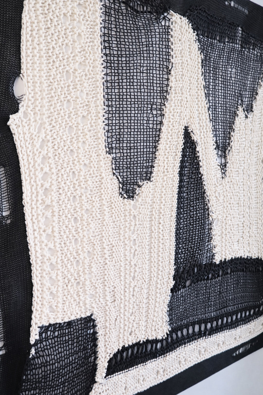 Side view of dimensional textile wall art showing depth of layered knit and mesh construction in black and cream