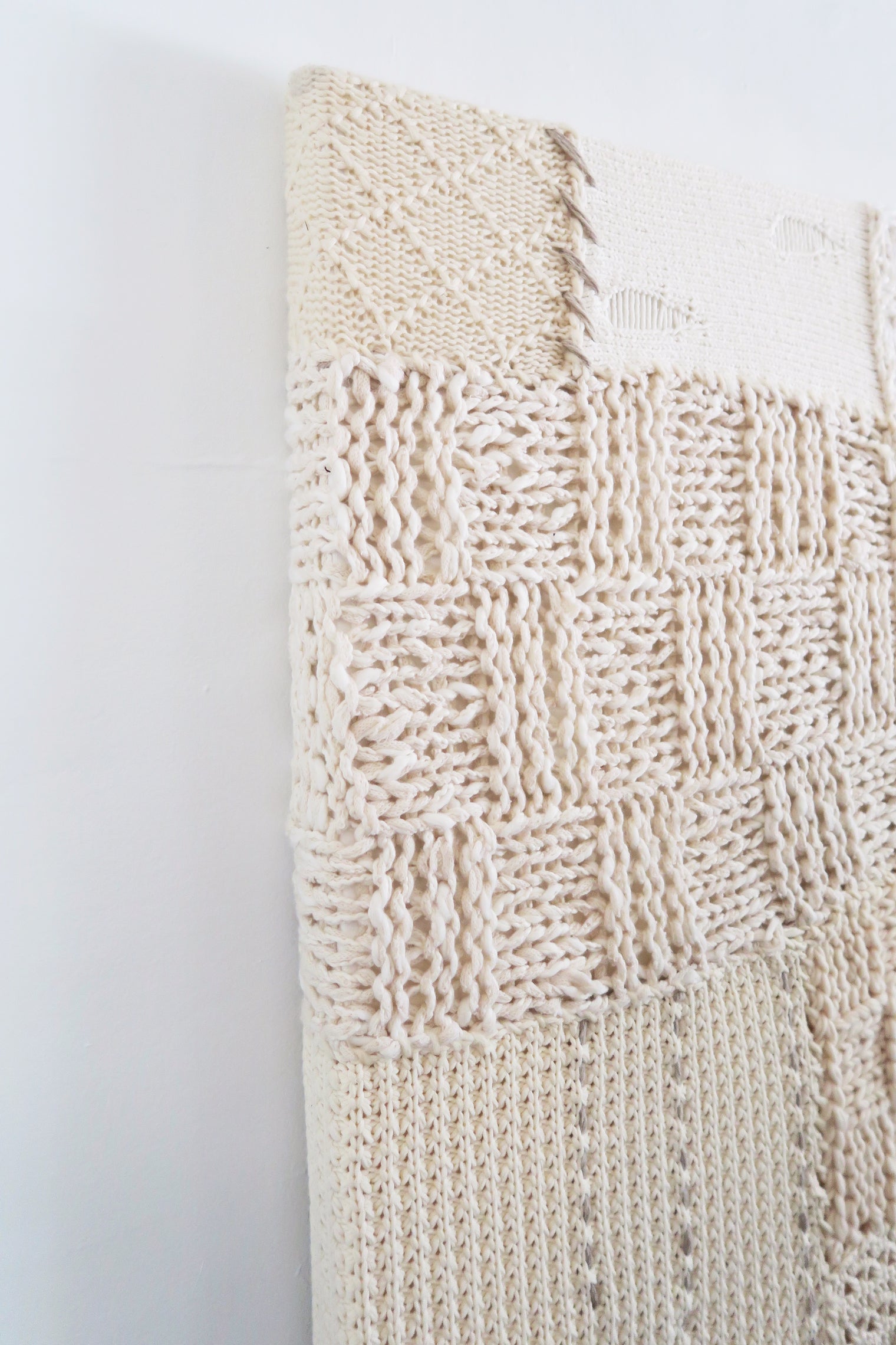 Lace knit and wool box stitch detail in handcrafted textile artwork made from cotton and cashmere yarns