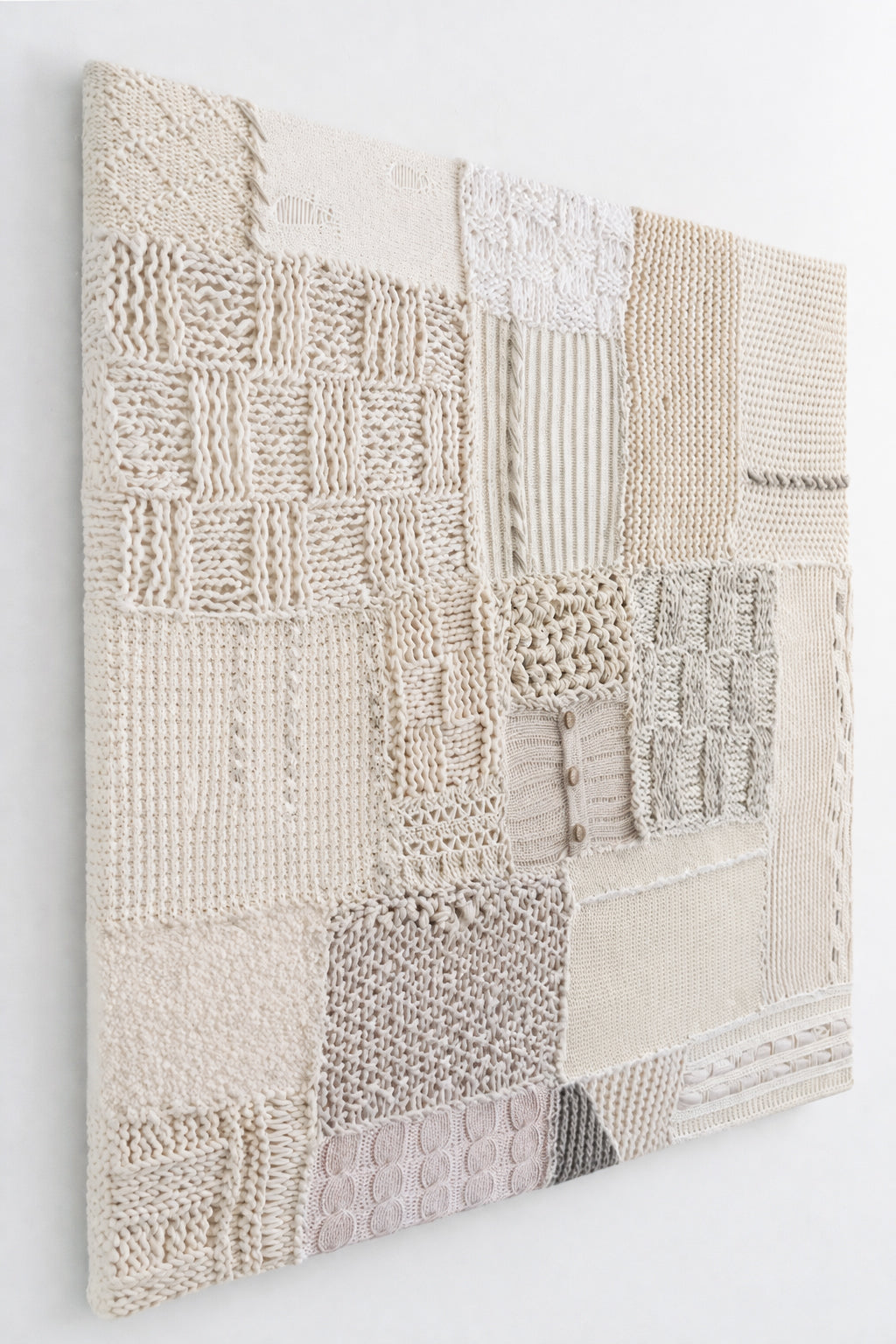 Side angle view of hand-stitched textile wall art detail showing embroidery and whip stitch construction on knit panels