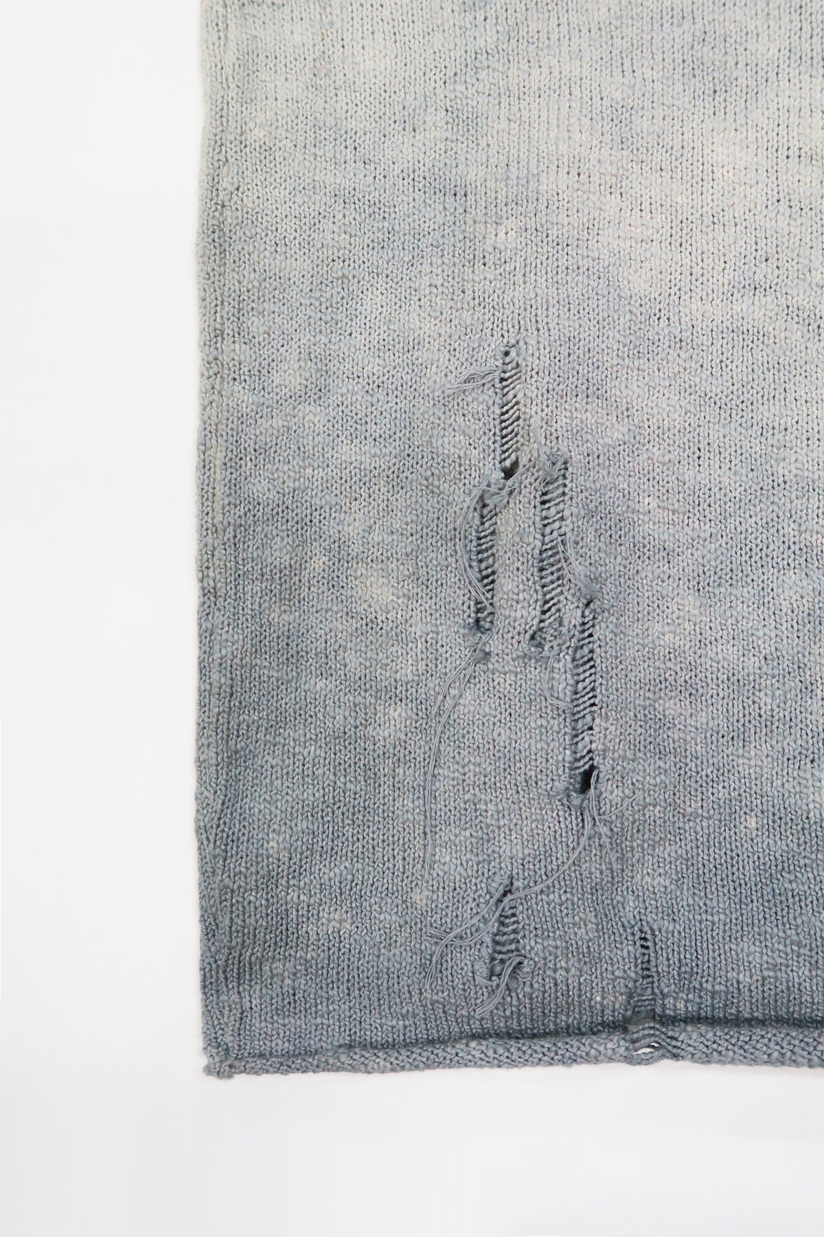 Close-up of hand-distressed knit and raw hem on the Suss Knits Archive Finish Raglan matrix inspired knit with grey hand dye technique