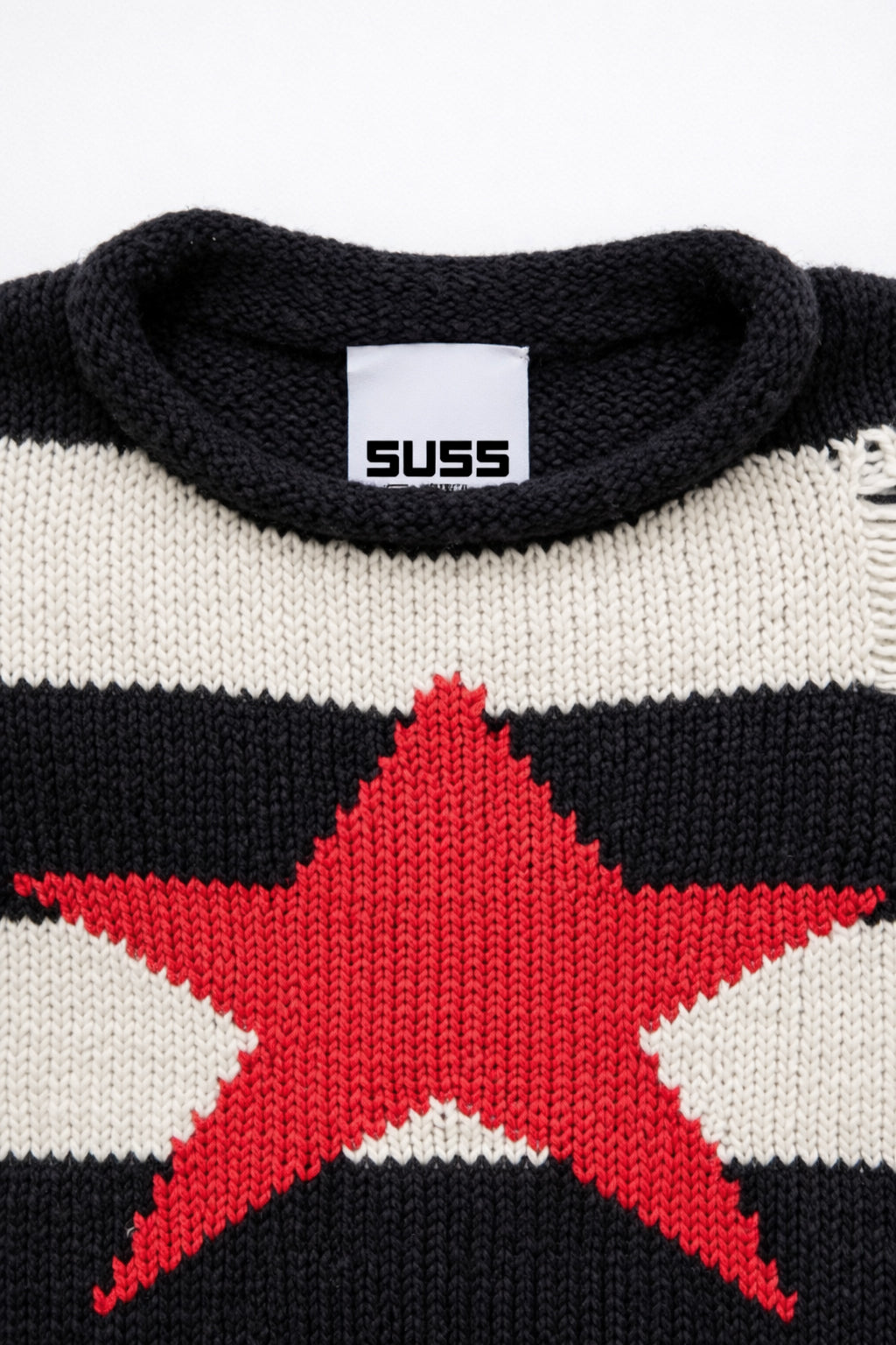 Detail of rollneck, round, neckline of black and cream striped distressed sweater with intarsia red star by Suss Knits