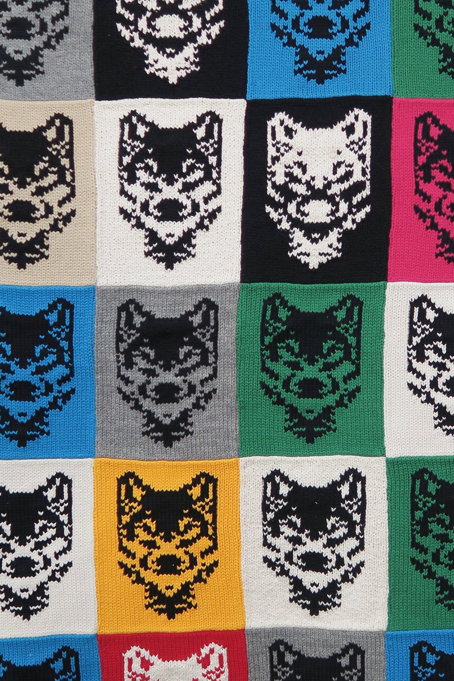 Close-up of hand-knit wolf motif panels in cotton showing texture and stitching detail