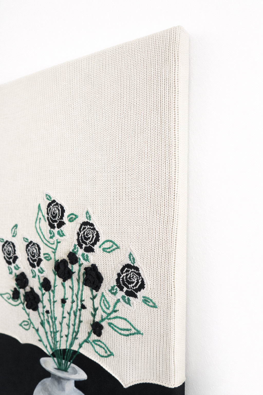 top right angled view of mixed media textile wall art combining knit, embroidery, and painting