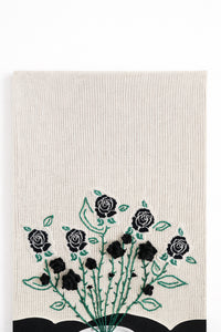 close up of hand loomed cotton knit background textile with embroidered vines and black rose details
