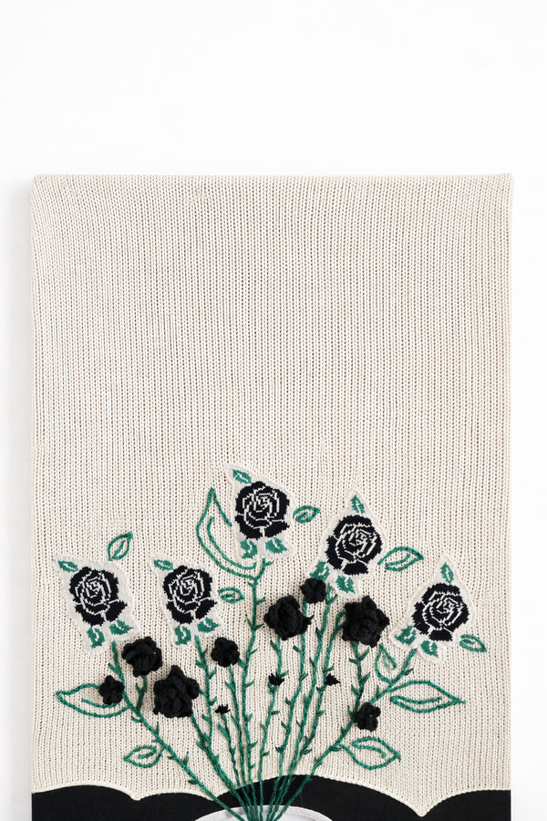 close up of hand loomed cotton knit background textile with embroidered vines and black rose details