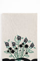 close up of hand loomed cotton knit background textile with embroidered vines and black rose details