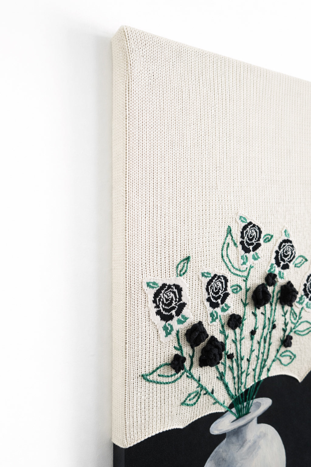 left top angled view of mixed media textile wall art combining knit, embroidery, and painting