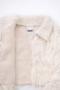 Close-up of hand loomed cotton knit base open front with layered cream viscose fringe detailing
