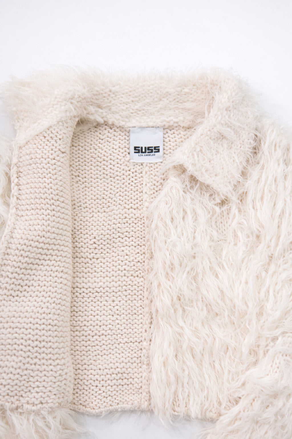 Close-up of hand loomed cotton knit base open front with layered cream viscose fringe detailing