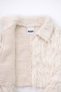 Close-up of hand loomed cotton knit base open front with layered cream viscose fringe detailing
