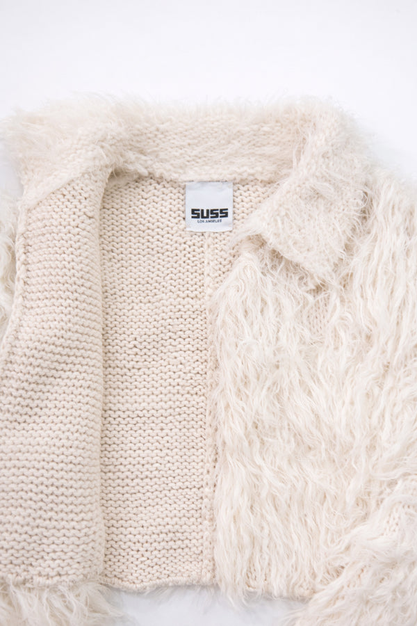Close-up of hand loomed cotton knit base open front with layered cream viscose fringe detailing