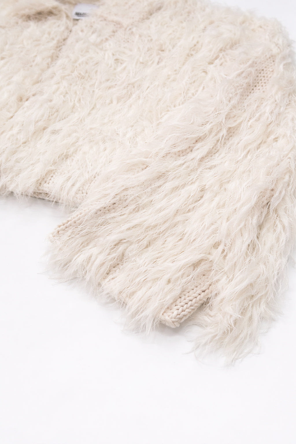 Close-up of dense cream fringe texture sleeve angle view on hand loomed cropped jacket