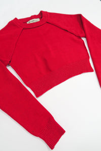 The Suss Knits bright Red Open Raglan Knit Top angled flat lay showing ribbed hem and cuff with cut out front detail.