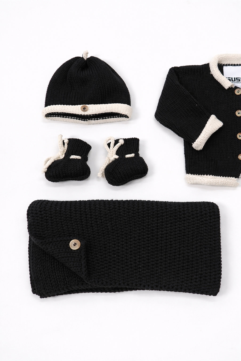 Close up of cotton knit black and cream baby beanie and booties handmade knit set
