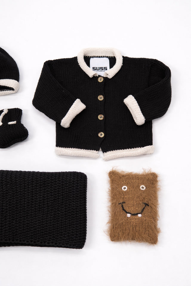 Close up of set of cotton black and cream baby cardigan and knit texture detail