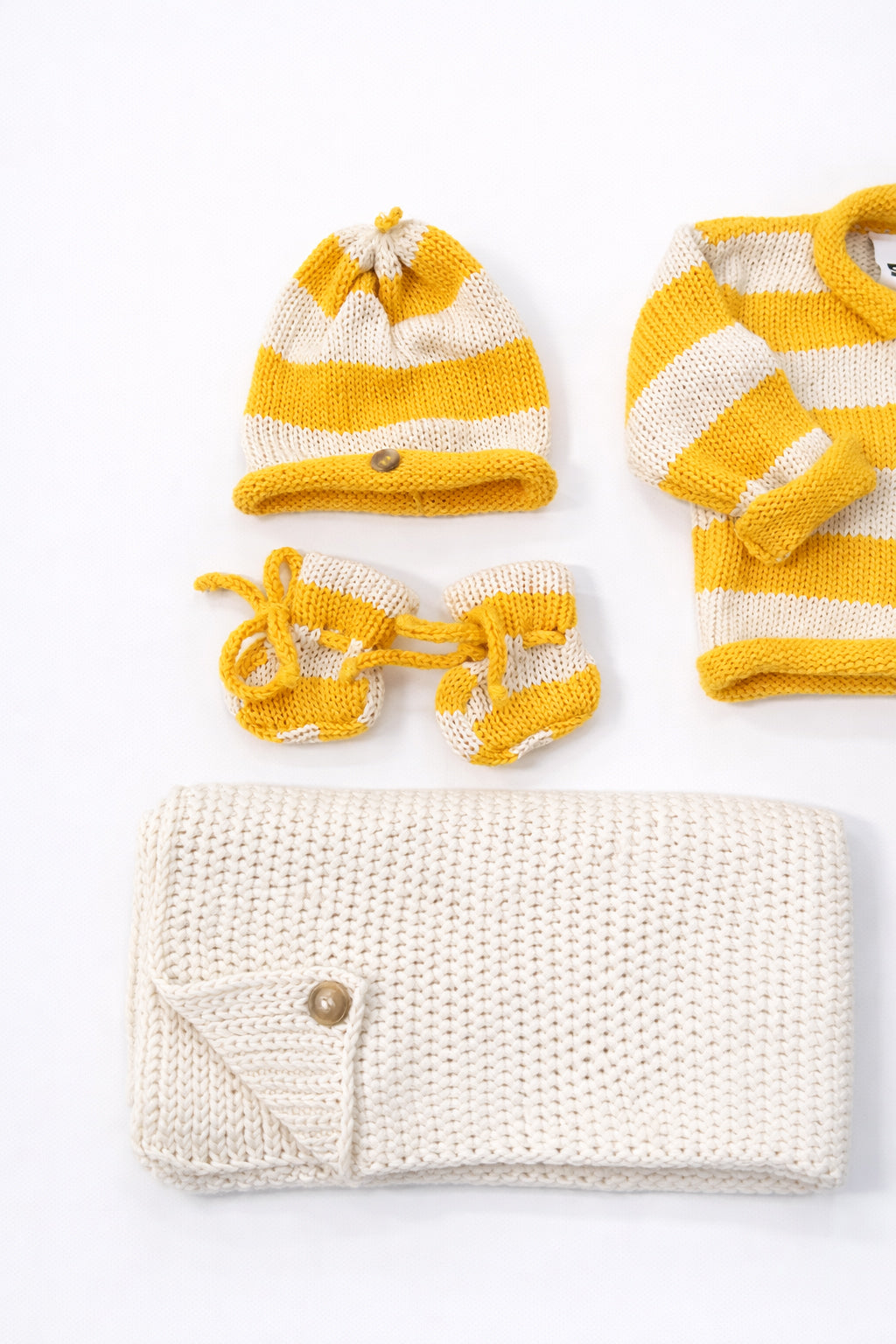 Close up of cotton yellow striped baby beanie and booties handmade knit set