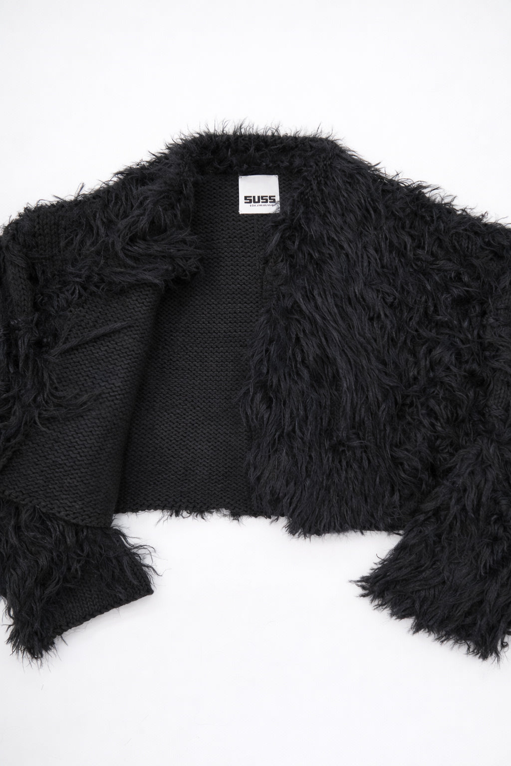 Detailed view of black fringe knit jacket showing contrast between structured knit and soft fringe