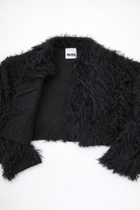 Detailed view of black fringe knit jacket showing contrast between structured knit and soft fringe