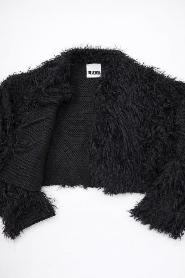 Detailed view of black fringe knit jacket showing contrast between structured knit and soft fringe