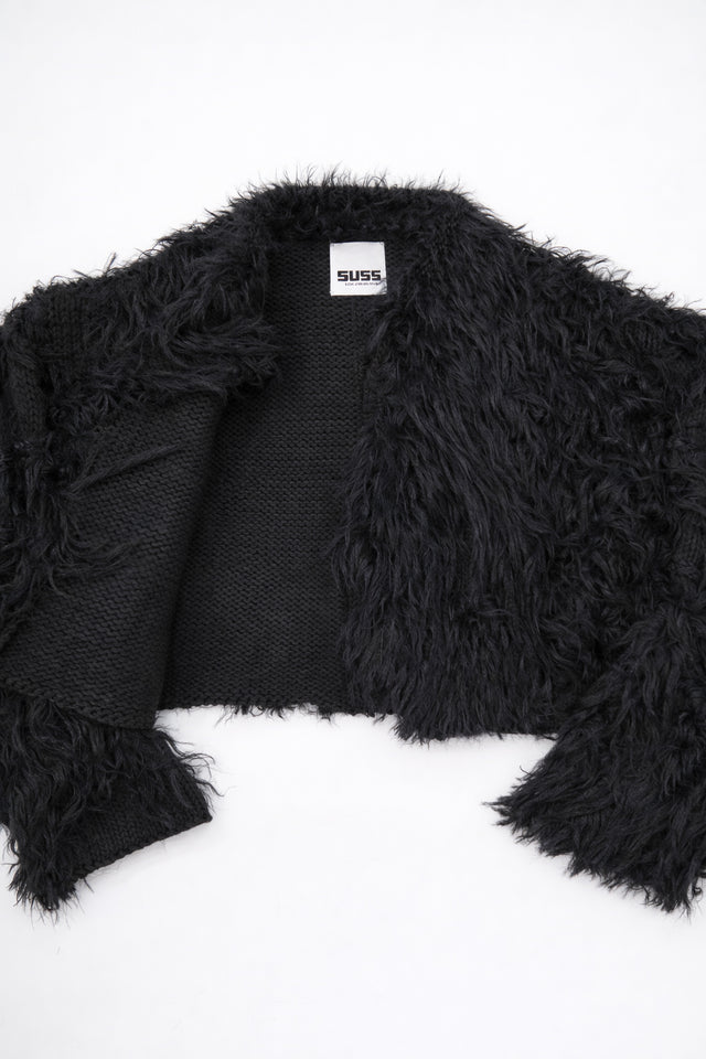 Detailed view of black fringe knit jacket showing contrast between structured knit and soft fringe