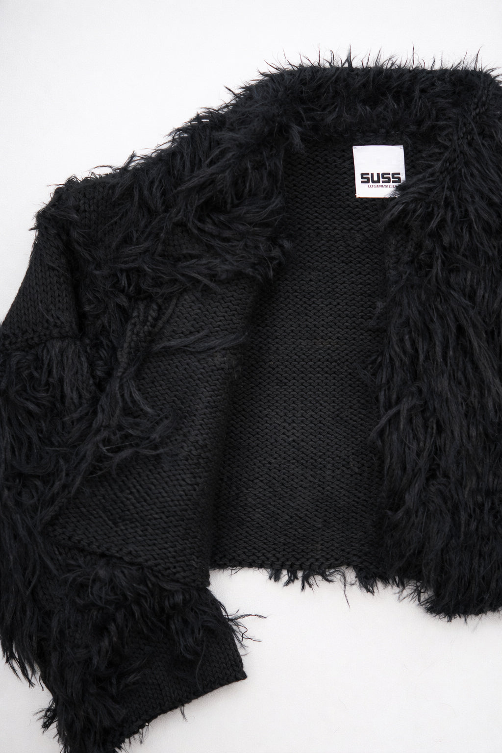 Close-up of hand loomed cotton knit base with layered black viscose fringe detailing