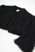 Textural close-up of black viscose fringe creating soft movement on cropped knit jacket