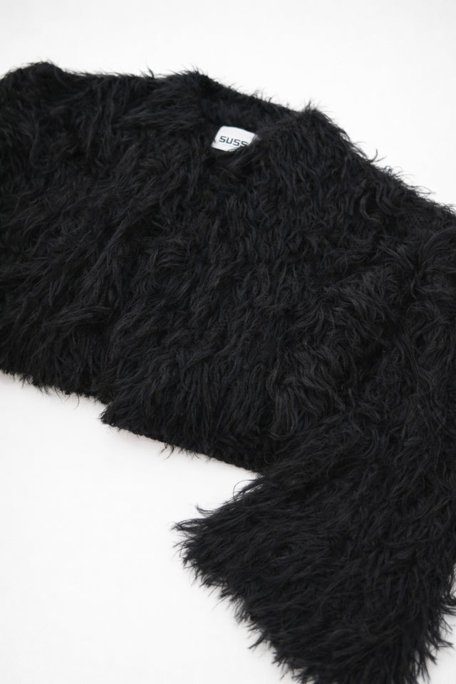Textural close-up of black viscose fringe creating soft movement on cropped knit jacket