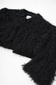 Textural close-up of black viscose fringe creating soft movement on cropped knit jacket