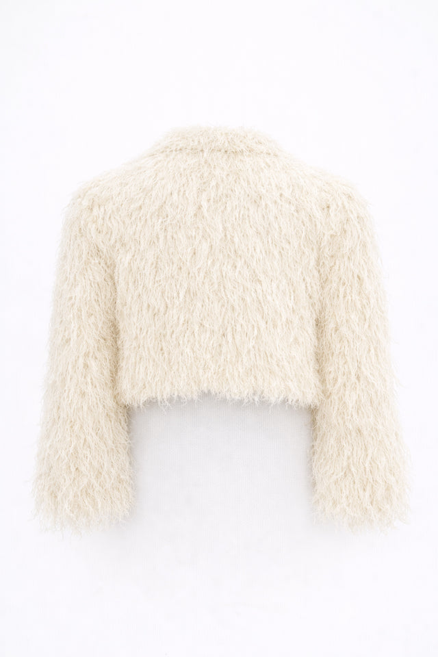 Back view of cream cropped fringe jacket with hand loomed knit base and layered viscose fringe texture