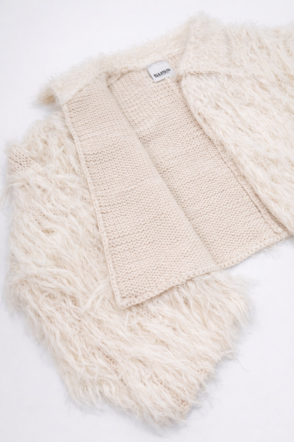Detailed view of cream fringe knit jacket showing contrast between structured knit inside and soft fringe at angle