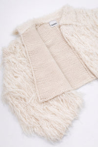 Detailed view of cream fringe knit jacket showing contrast between structured knit inside and soft fringe at angle