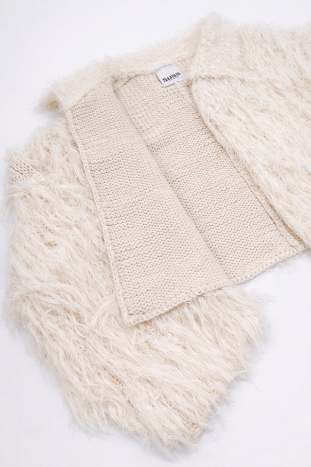 Detailed view of cream fringe knit jacket showing contrast between structured knit inside and soft fringe at angle
