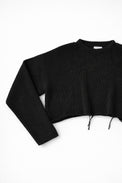 Close-up of black knit sweater sleeve angled showing soft textured stitch