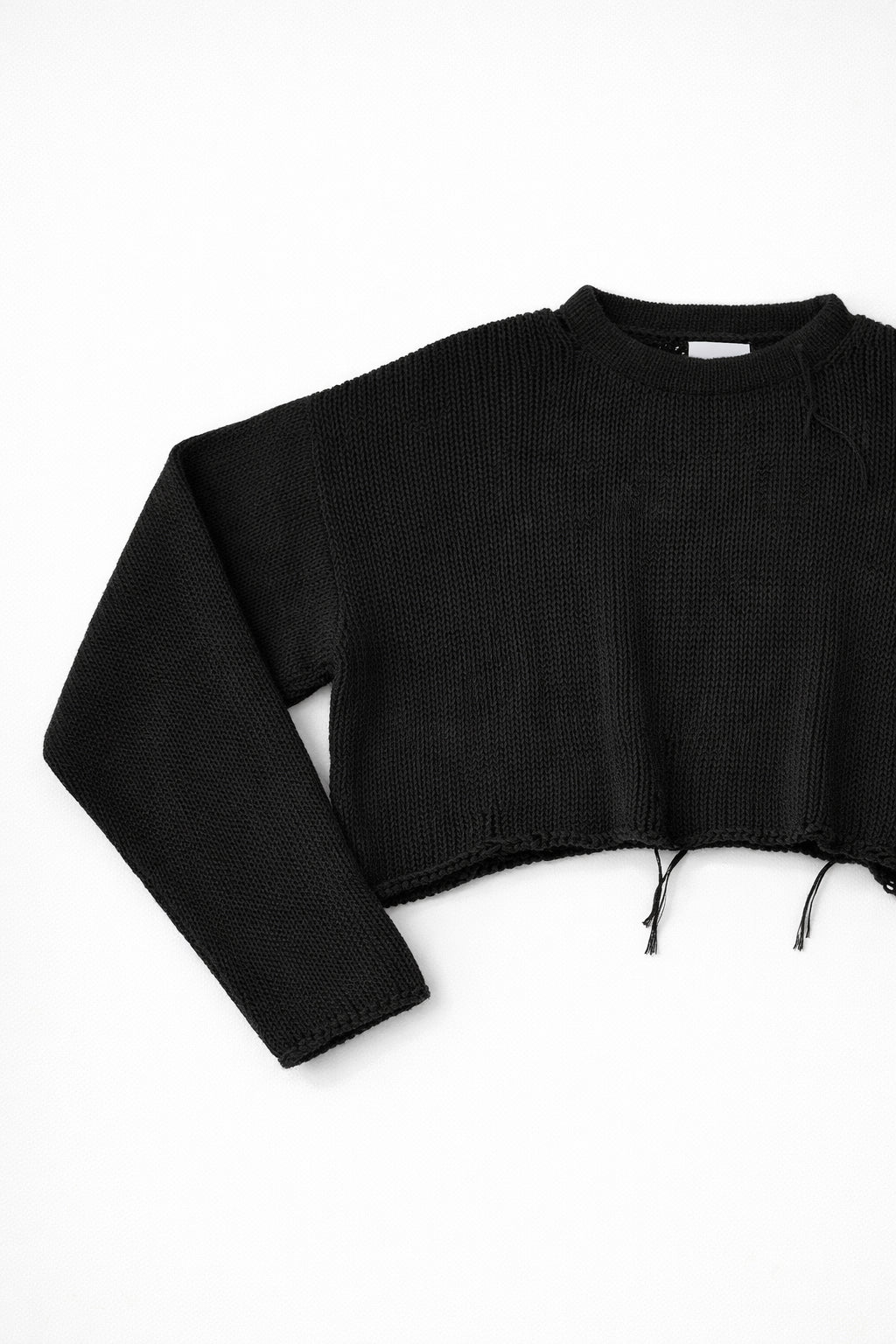 Close-up of black knit sweater sleeve angled showing soft textured stitch