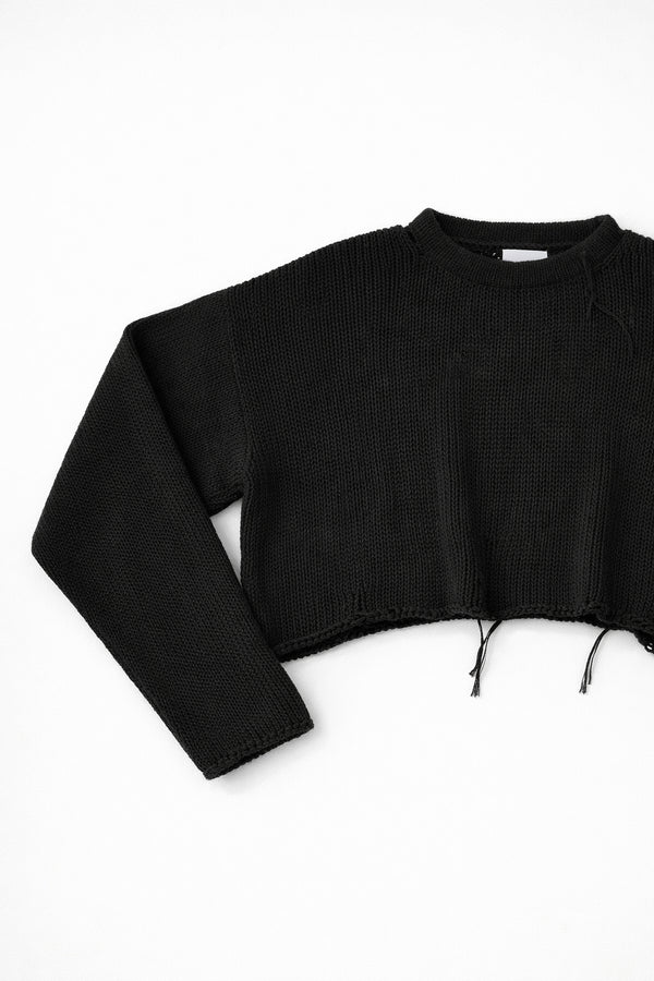 Close-up of black knit sweater sleeve angled showing soft textured stitch