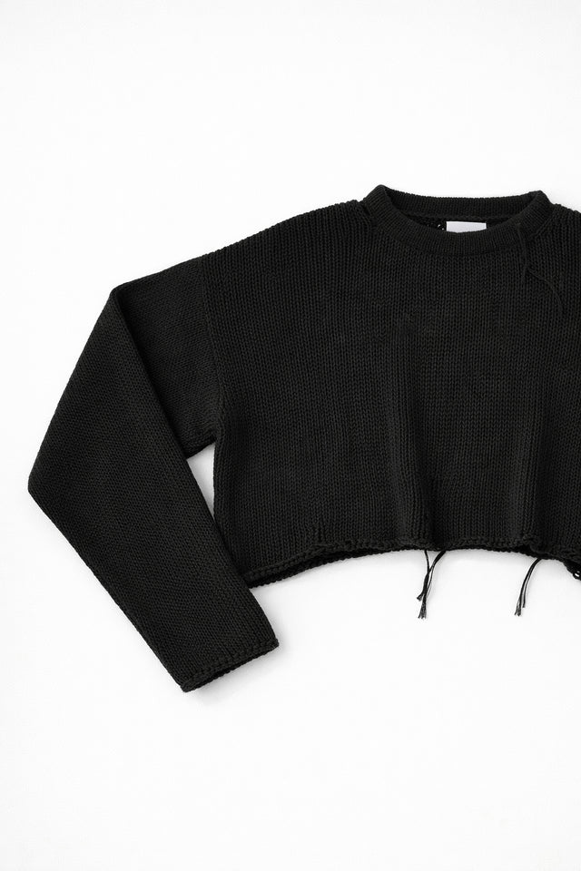 Close-up of black knit sweater sleeve angled showing soft textured stitch