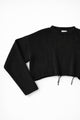Close-up of black knit sweater sleeve angled showing soft textured stitch