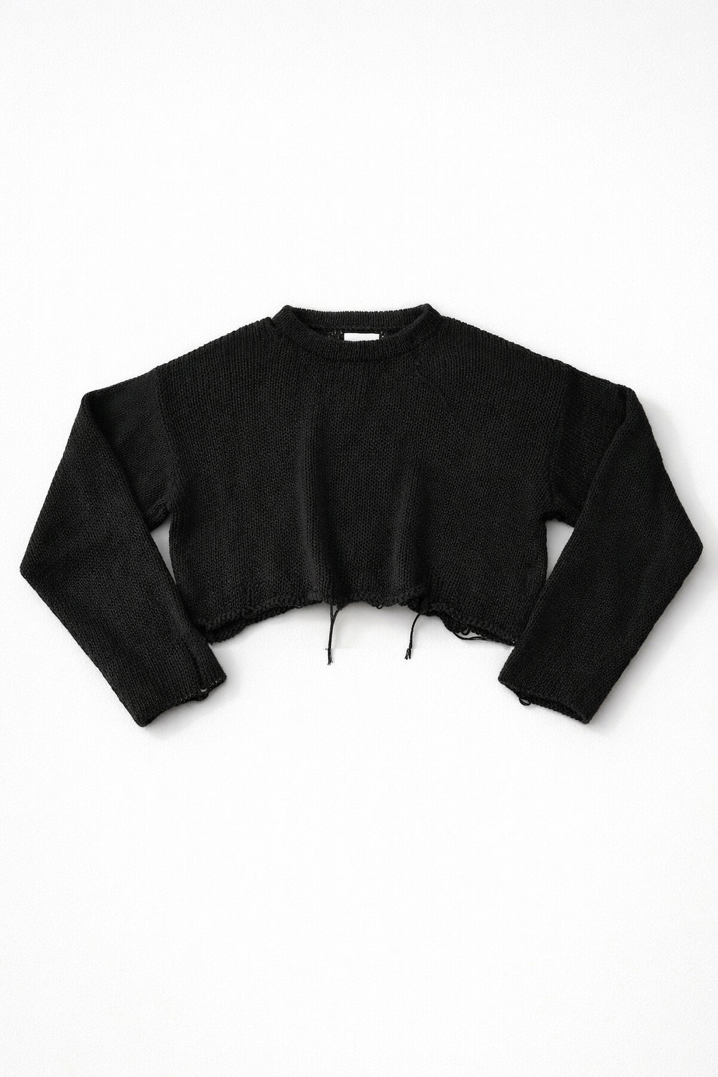 Black cotton cropped knit sweater laid flat with soft texture and raw hem detail