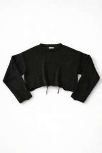 Black cotton cropped knit sweater laid flat with soft texture and raw hem detail