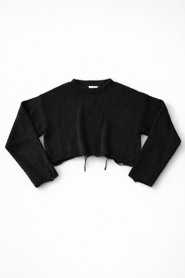 Black cotton cropped knit sweater laid flat with soft texture and raw hem detail