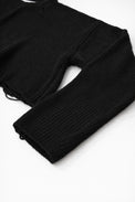 Close-up of black cotton knit sweater sleeve showing soft textured stitch