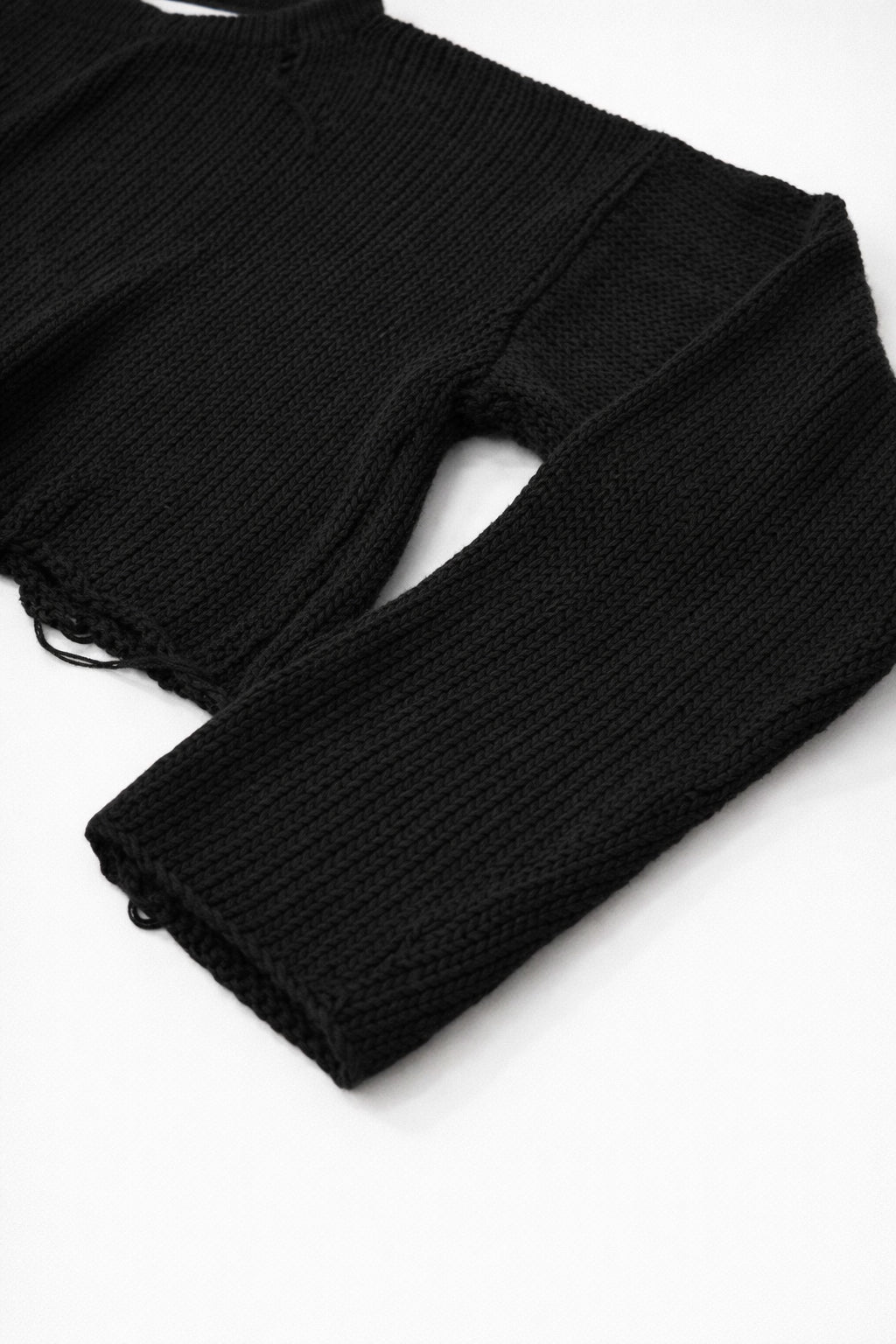 Close-up of black cotton knit sweater sleeve showing soft textured stitch