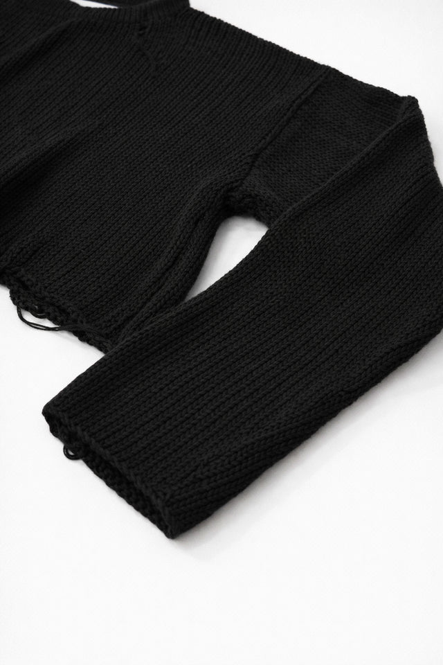 Close-up of black cotton knit sweater sleeve showing soft textured stitch