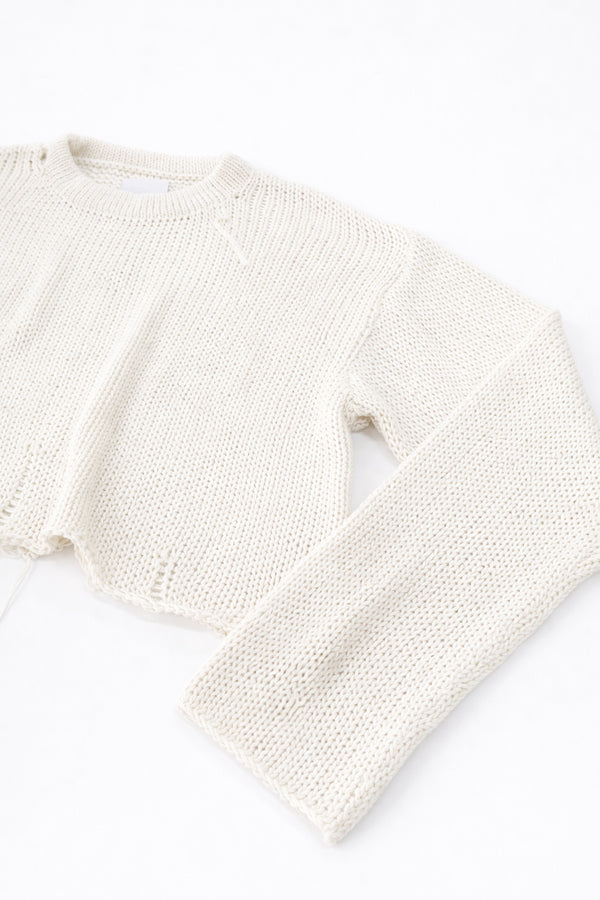Side detail of raw edge sleeve cuff in cream cotton knit