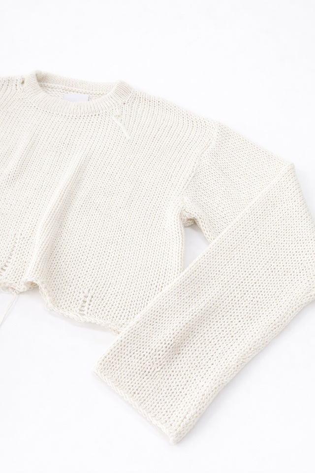 Side detail of raw edge sleeve cuff in cream cotton knit